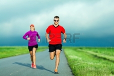 20439088-man-and-woman-runners-running-on-country-road-in-summer-sunset